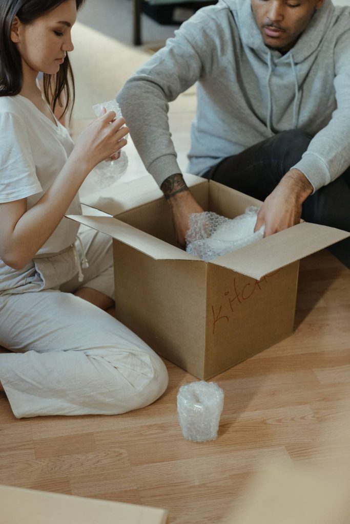 man and woman packing glassware in a moving box